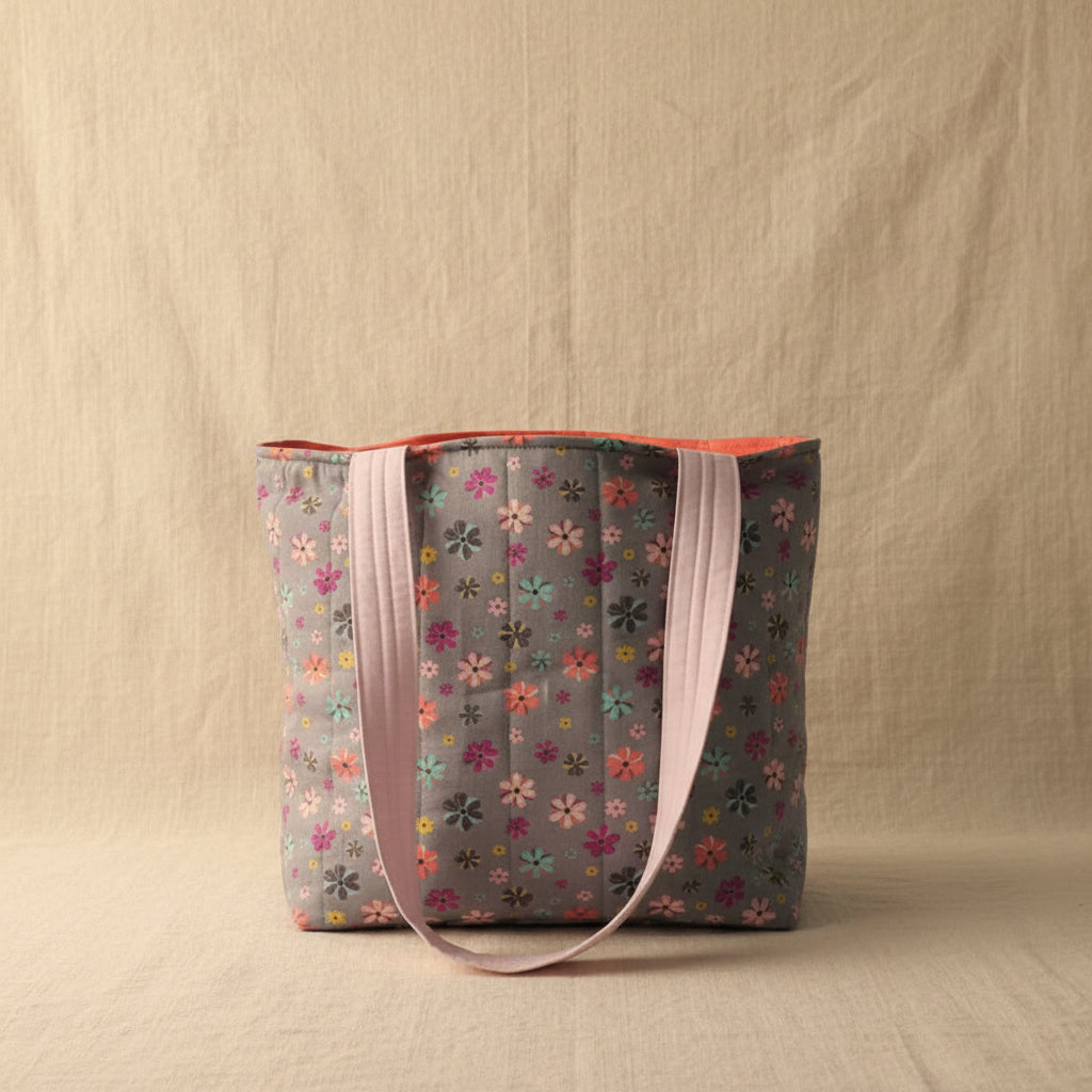 Front view of gray hand-quilted floral tote with pink handles