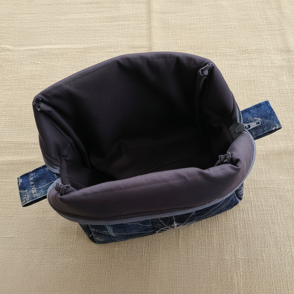 Open navy quilted cosmetic bag showing dark gray interior lining and map print exterior