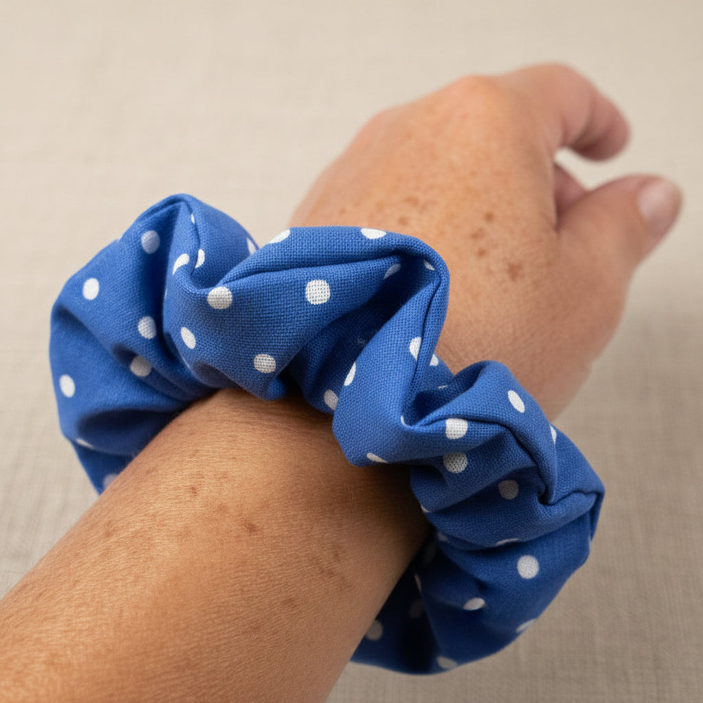 Blue polka dot hair scrunchie worn as a bracelet on freckled wrist