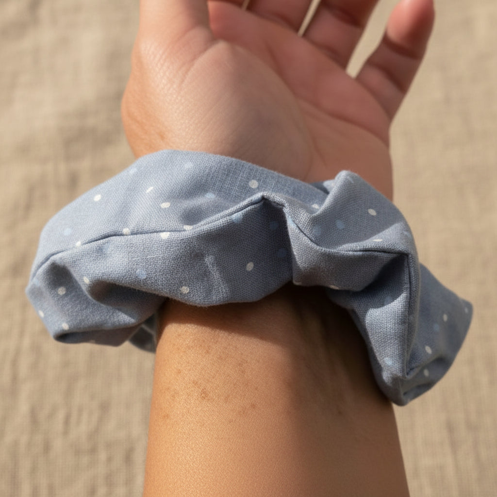 Dusty blue cotton scrunchie with white polka dots on wrist