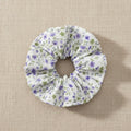 Flat lay of homemade white with tiny lilac flowers scrunchie