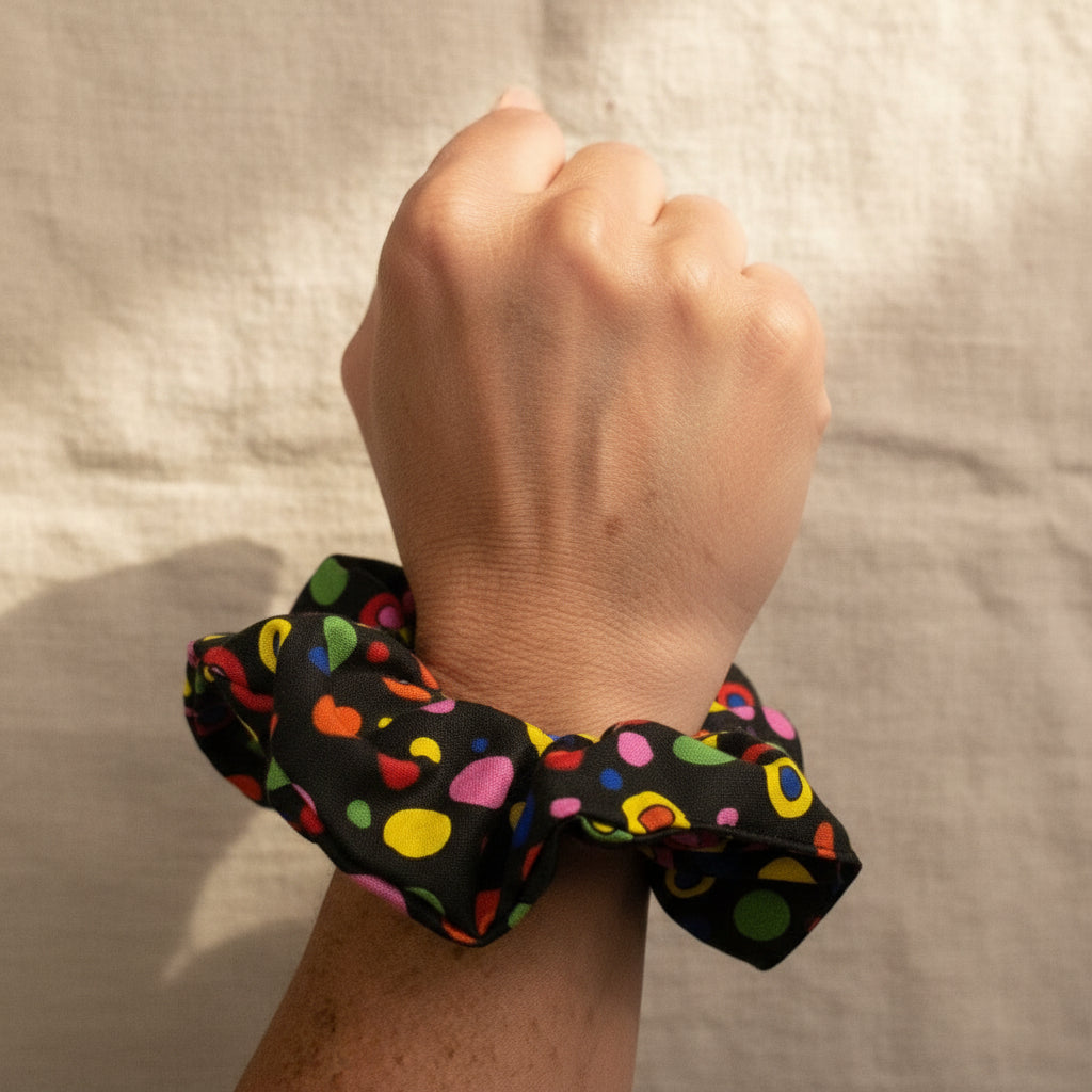 Black dotted rainbow scrunchie worn as a wrist accessory
