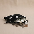 Polka dot coin purse holding coins, cards, and earbuds