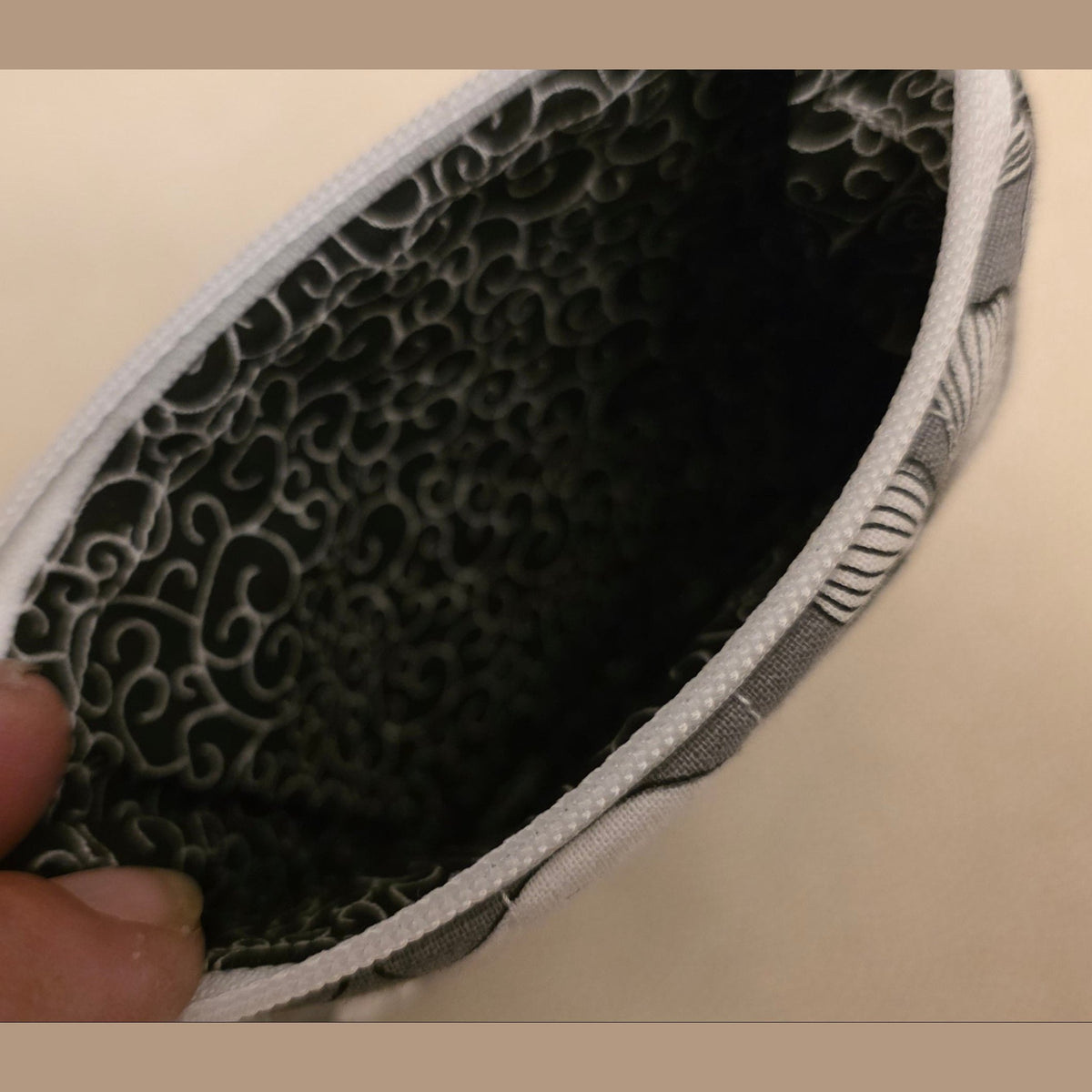 Close up of charcoal interior lining with scrollwork pattern in grey floral quilted pouch