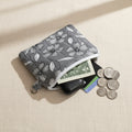 Grey hand quilted mini pansy pouch with white floral pattern holding coins and earbuds