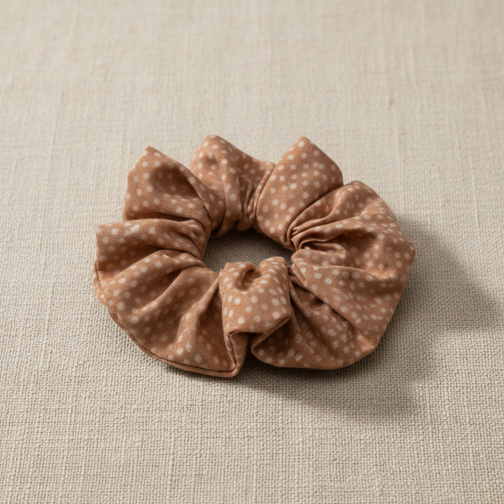 Top-down view of speckled dusty rose fabric scrunchie