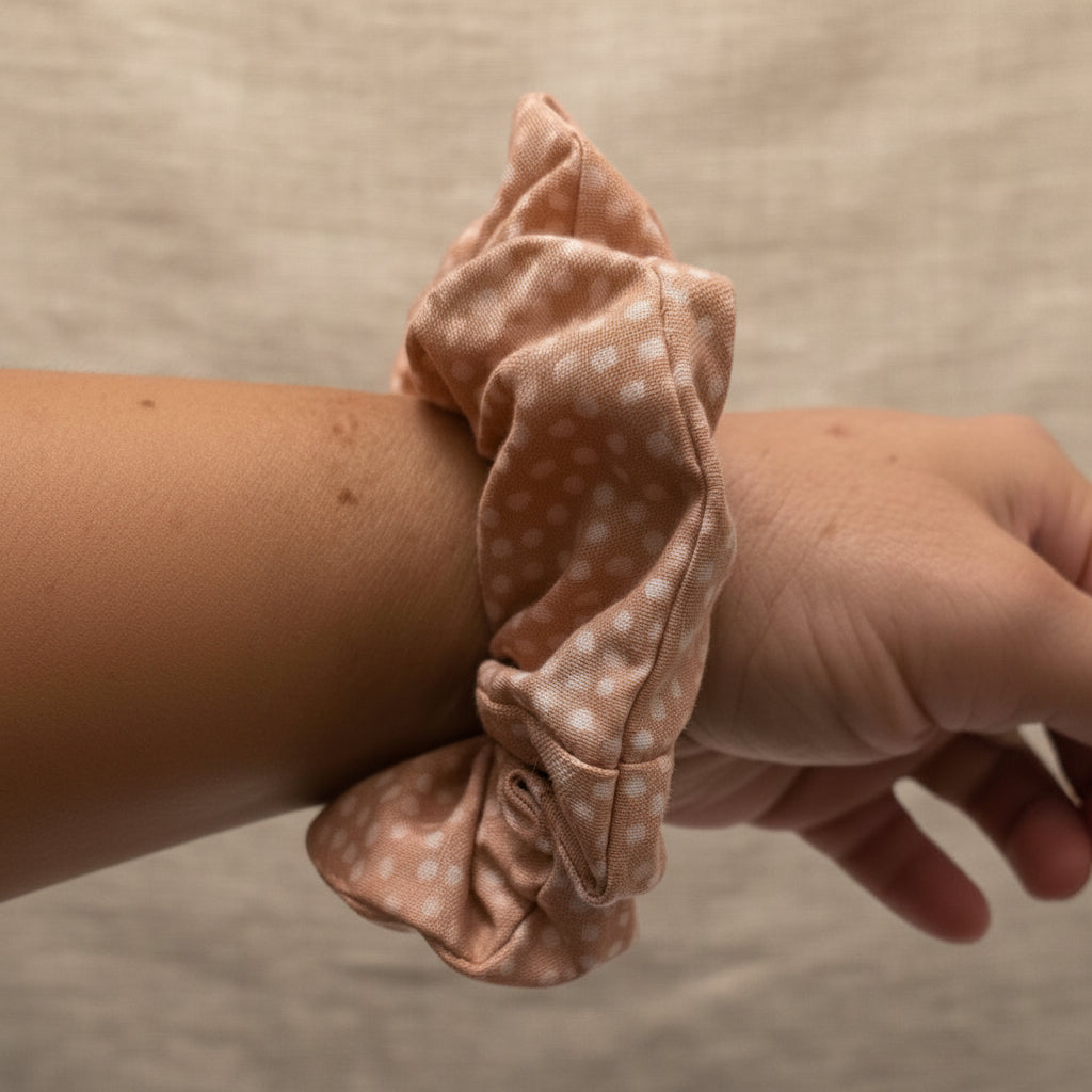 Dusty rose speckled hair tie worn on wrist with freckles