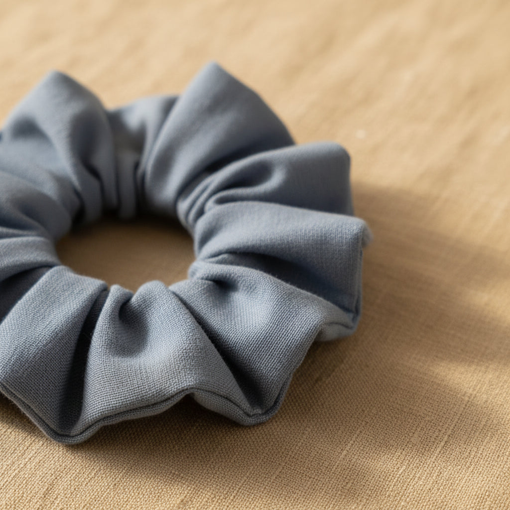 Close-up of dusty blue hair scrunchie with deep pleats and woven fabric grain
