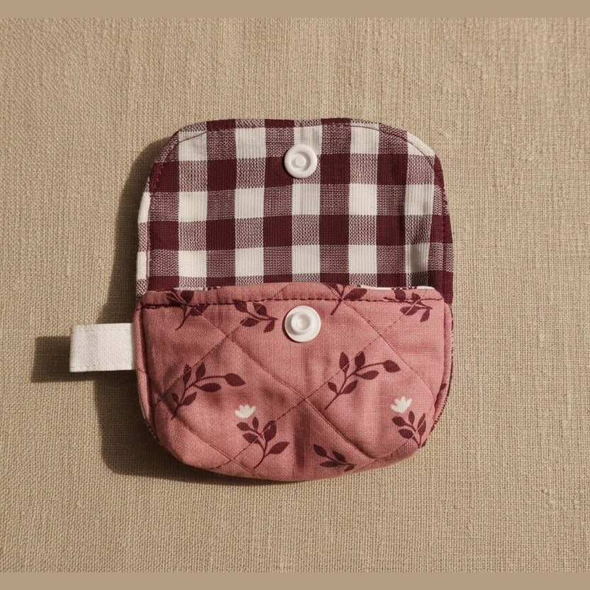 A small fabric pouch with a snap-button closure, shown open against a plain beige background. The top flap has a maroon and white gingham pattern, and the front pocket is dusty pink with a dark floral print.