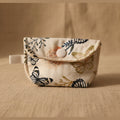 A small fabric pouch with a snap button closure, featuring a cream-colored background with a butterfly pattern in navy blue, orange, and gold.