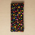 A rectangular black fabric pouch or sleeve with a colorful retro concentric circle dot pattern, hanging against a plain beige wall.