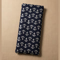 A rectangular navy blue fabric pouch or sleeve with a repeating white anchor pattern, shown against a plain beige wall.