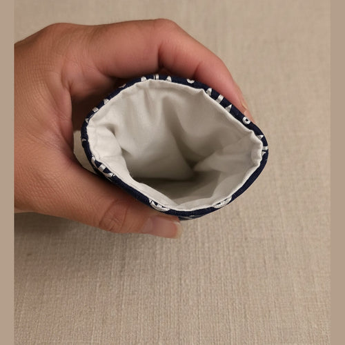 A close-up of a hand holding the open end of a fabric-covered sleeve, showing a white interior lining and a dark navy exterior with a small white pattern near the edge.