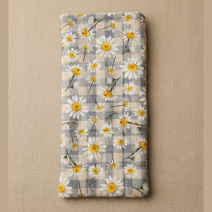 A rectangular fabric item, likely a pouch or sleeve, featuring a daisy and plaid pattern in gray, white, and yellow, photographed against a plain beige background.