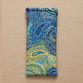 A rectangular fabric pouch with a blue, green, and yellow paisley pattern, hanging against a plain beige wall.