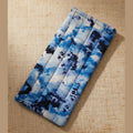 A rectangular zippered pouch with a blue and white tie-dye pattern, shown against a plain beige wall.