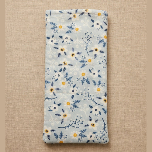 A rectangular fabric pouch or sleeve with a light blue background and a white, navy, and yellow floral pattern, shown against a plain beige background.
