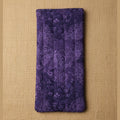 A rectangular quilted fabric pouch in deep purple with a lighter purple butterfly and floral pattern, shown flat against a plain beige background.