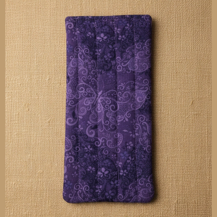 A rectangular quilted fabric pouch in deep purple with a lighter purple butterfly and floral pattern, shown flat against a plain beige background.
