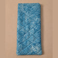 A blue quilted fabric pouch with a white dragonfly pattern, shown on a solid peach-colored background.