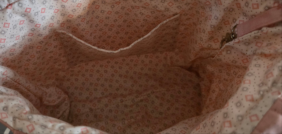 Close-up of the inside of a fabric bag or pouch with a small geometric floral print in pink and beige.