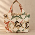 A handmade quilted tote bag with geometric star patterns in cream, green, orange, and black.