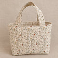 A small fabric tote bag with a cream-colored background and a delicate brown floral and vine pattern, featuring two top handles.