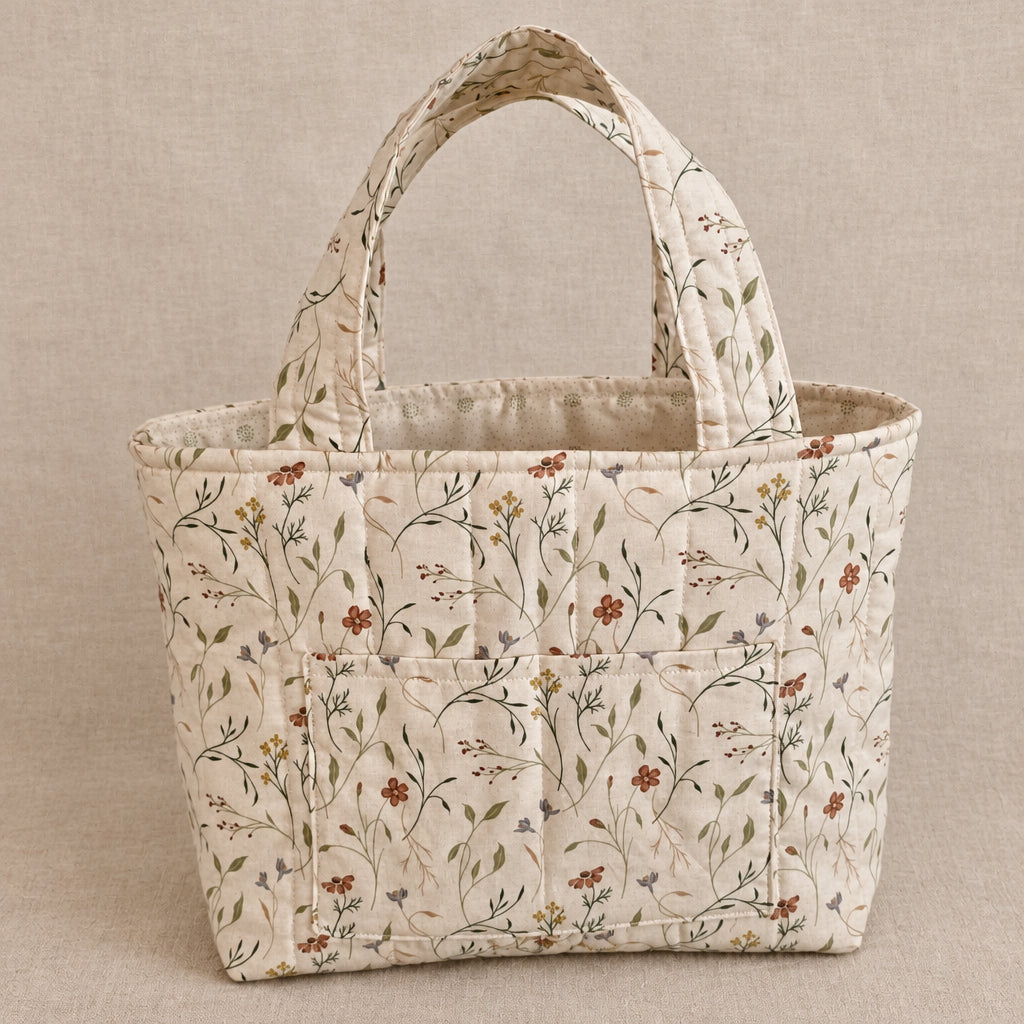 A small fabric tote bag with a cream-colored background and a delicate brown floral and vine pattern, featuring two top handles.