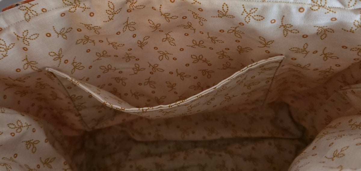 Close-up of a beige fabric interior with a small brown floral print, showing a side pocket.